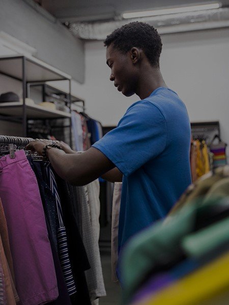 A young african shop attendant rearranging his fashion items.