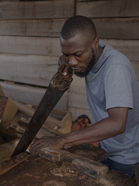 An african carpenter cutting wood